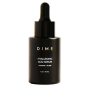 Black serum bottle labeled 'DIME' on a beige background